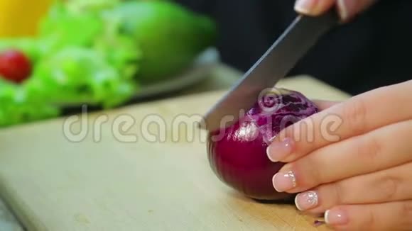 女性手在木板上用刀切一个红色洋葱视频的预览图