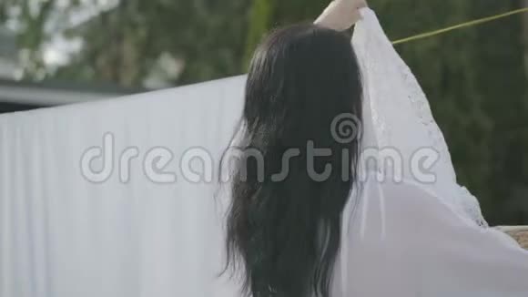 在户外的晾衣绳上悬挂着白色衣服的长发的迷人女人的后景华盛顿女孩视频的预览图