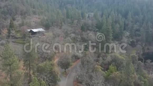 飞越森林经过俄勒冈州一座由树木环绕的小木屋4k空中飞行视频的预览图