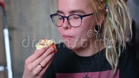 一个不寻常的女孩头上戴着可怕的东西穿着刺在咖啡馆里吃蛋糕一个戴眼镜的年轻女子视频的预览图