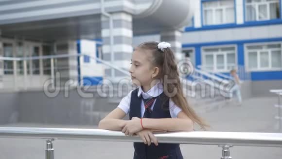 校园里穿着校服的漂亮小女孩在一栋小学大楼前的肖像视频的预览图