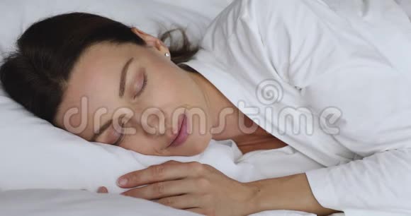 平静安详的年轻女子迷人的脸躺在舒适的床上视频的预览图