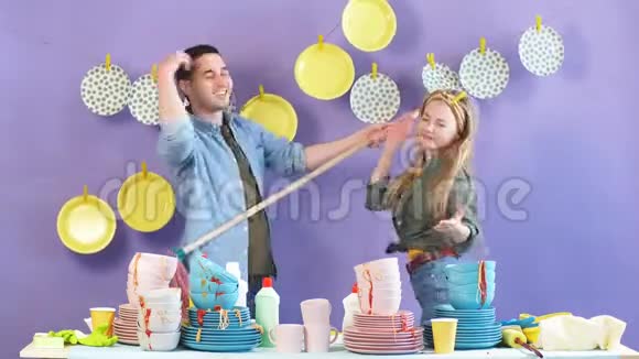 年轻有趣的男人和女人用清洁工具唱歌跳舞视频的预览图