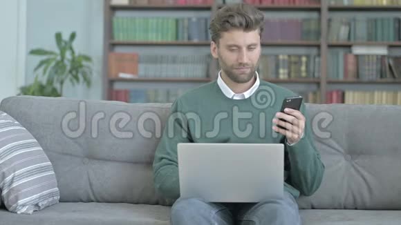 勤劳的人在检查他的手机时用手提电脑视频的预览图