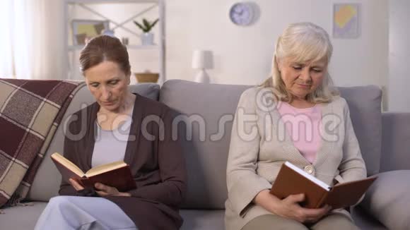 两个嫉妒的老女人坐在疗养院的大厅里看书竞争视频的预览图