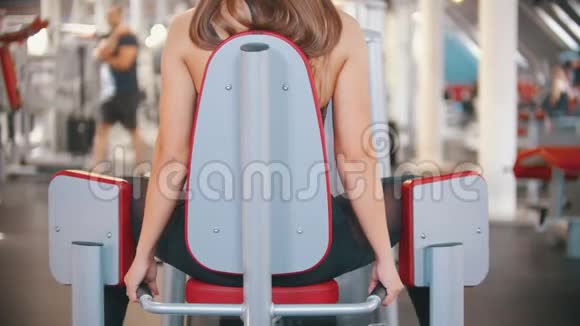 一位在健身房做长头发训练的女运动员在蝴蝶训练装置上锻炼传播视频的预览图