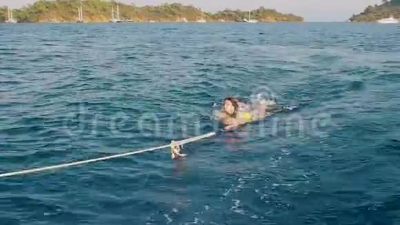一个年轻的女人在船上从水中抽出来在一艘抓住绳子的船后游泳视频的预览图