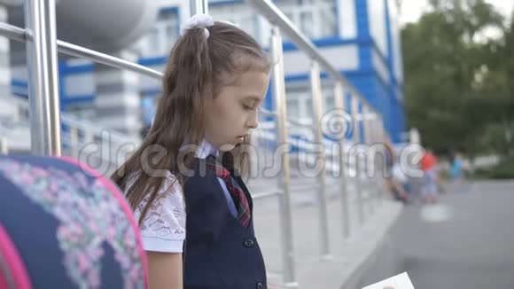 穿着校服的女孩在学校里翻阅教科书阅读老师的指示视频的预览图