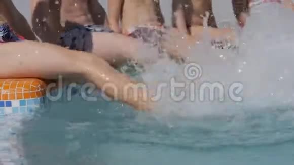 孩子们坐在池边溅起双脚双腿合拢孩子们在游泳池里度假视频的预览图