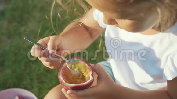 在户外慢动作吃西番莲的可爱小女孩的特写镜头视频的预览图