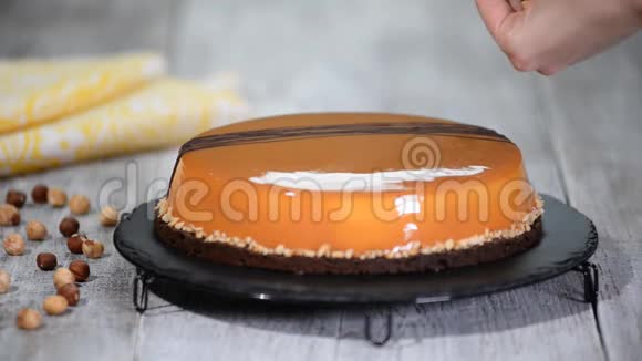 甜点女人用镜子釉装饰榛子焦糖慕斯蛋糕视频的预览图