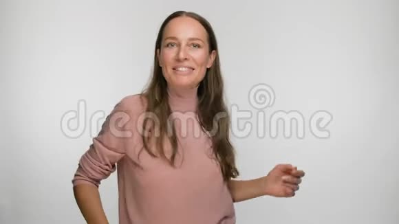 穿着粉色上衣在白色背景下跳舞的无忧无虑的女人视频的预览图