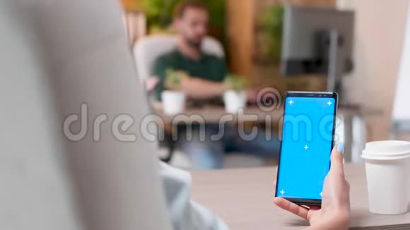 女人拿着一部手机上面有一个孤立的蓝色屏幕模型视频的预览图
