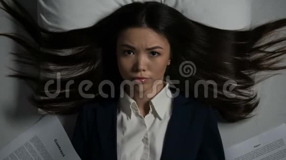年轻的年轻的亚洲女人身上堆满了文件在床上消失工作过度视频的预览图