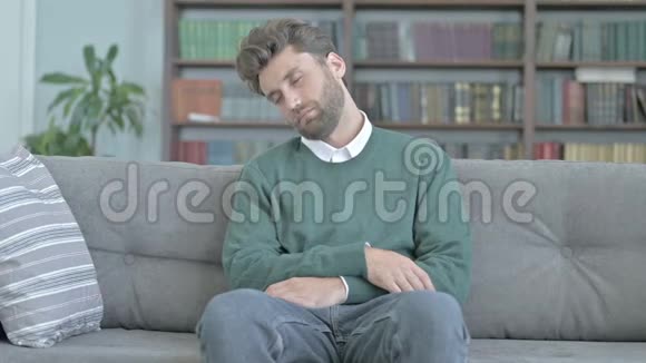 疲惫的年轻人坐在沙发上小睡片刻视频的预览图