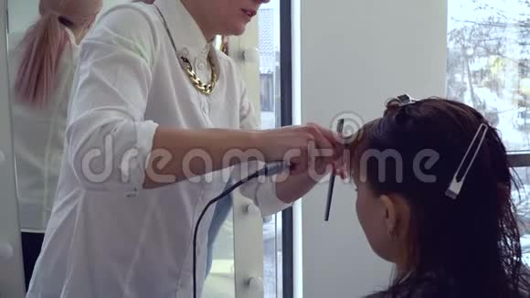 美容院理发店发型师给理发女孩做热剪发型师进行大师班特写镜头慢慢视频的预览图