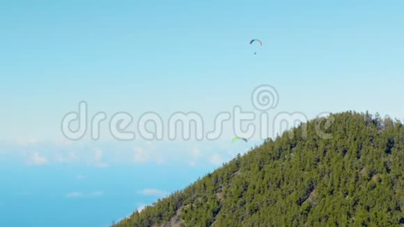 两个滑翔伞的轮廓飞过云雾笼罩的山谷视频的预览图