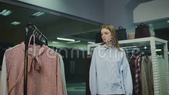 女人在买衣服的时候在时装店的衣架上看衣服视频的预览图