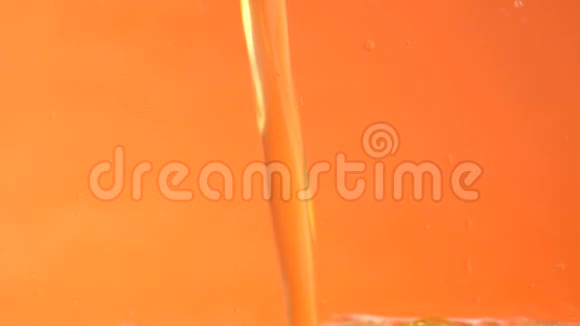 橙色柠檬水慢慢地倒在黄色背景上的透明玻璃上视频的预览图