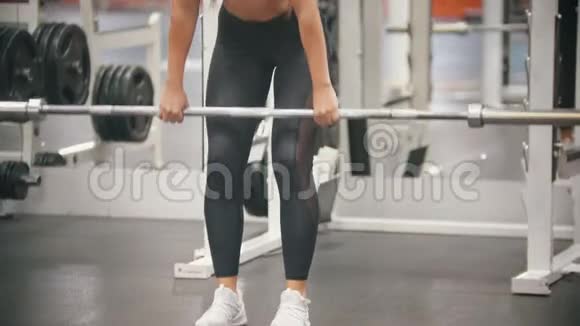 一位在健身房训练腿脚的运动员女子手里拿着一根铁杆身体向下倾视频的预览图