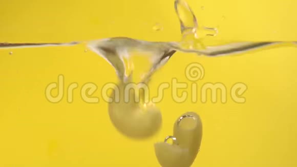 令人垂涎欲滴的意大利面在黄色背景下落入沸水慢动作视频的预览图