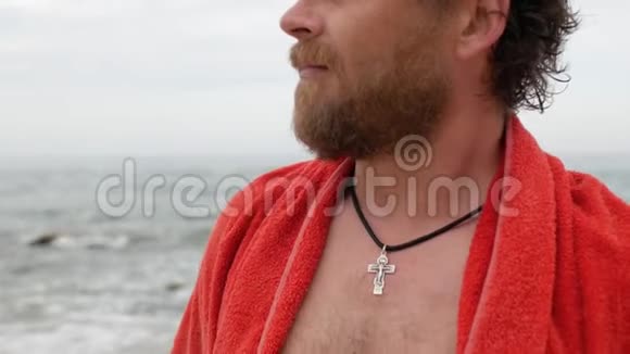 一个留着胡子蓝眼睛胸前戴着十字架的人在大海的背景下呼吸4公里视频视频的预览图
