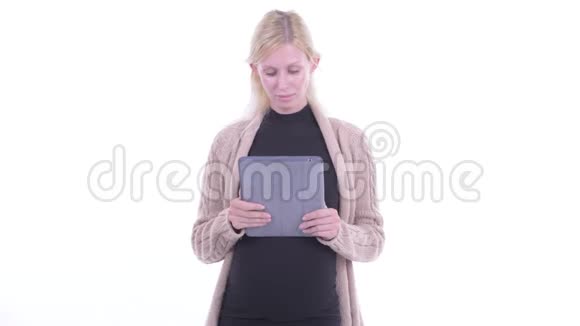 一位年轻的金发孕妇正在用数码平板电脑思考视频的预览图
