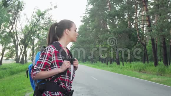 带背包在乡间小路上搭便车的迷人女人视频的预览图