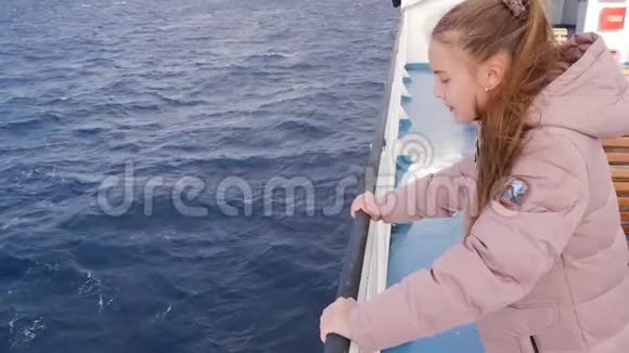 穿着粉红色夹克的女孩漂浮在船上游客在水海河上散步年轻的金发少年视频的预览图