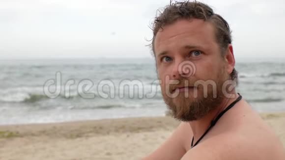 一个在大海背景上留着胡子的家伙正在用一把木梳梳理他的胡子4公里视频视频的预览图