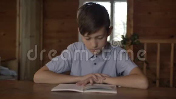 可怜的男孩坐在桌子旁看书视频的预览图