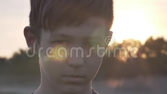 在麦田里愤怒的悲伤男孩的肖像看着日落时的镜头近在咫尺视频的预览图