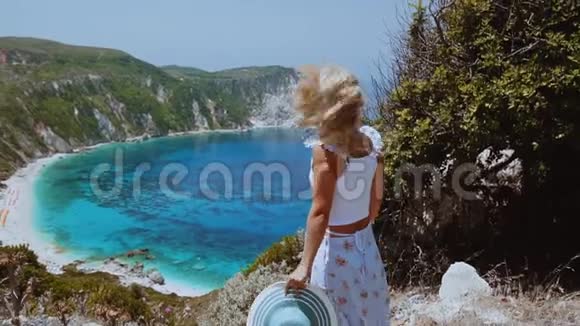 在希腊的凯法洛尼亚岛美丽的金发女人的慢莫在她的头发上微风幸福快乐视频的预览图