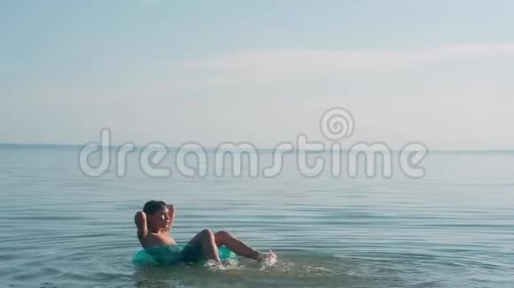 男孩漂浮在水上的蓝色充气圈上视频的预览图