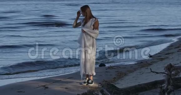 年轻的高加索女人站在海滩上看着海浪体贴的女孩在户外度过夏天的夜晚视频的预览图