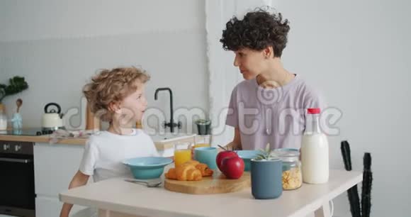 在家厨房吃早餐时年轻女子和小男孩说话视频的预览图