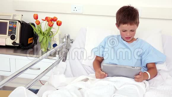 小病童坐在床上用平板电脑视频的预览图