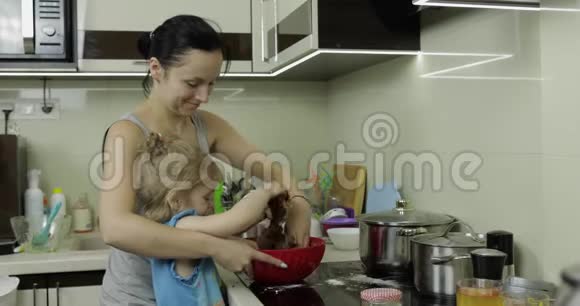 妈妈和女儿混合巧克力面团女孩在厨房做蛋糕视频的预览图