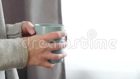 女孩喝一杯热茶或咖啡女人手拿着一个杯子杯子上有蒸汽视频的预览图