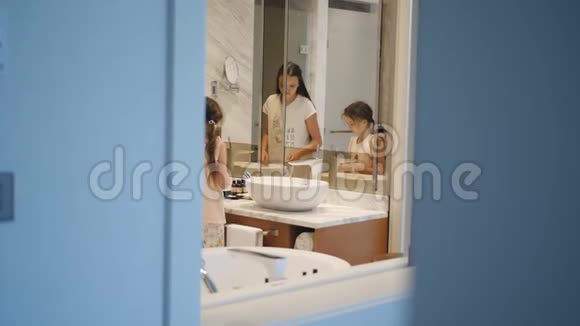 两个长发的姐妹穿着睡衣走进浴室在镜子前刷牙视频的预览图