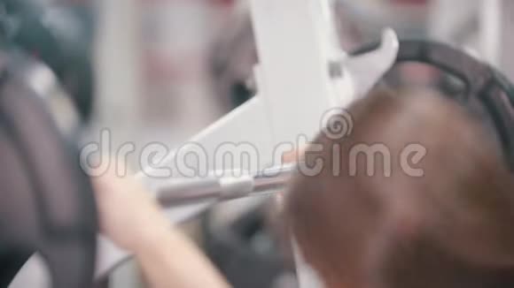 一个在健身房运动的女人站在哑铃下把它放在肩上视频的预览图