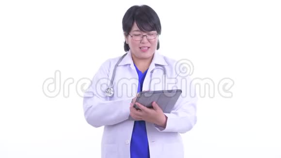 快乐超重亚洲女医生一边用数码平板一边说话视频的预览图