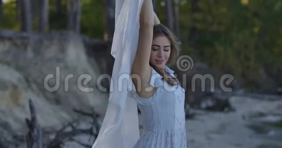 漂亮的白人女人站在森林里戴着被风吹过的浅白色围巾微笑着漂亮姑娘花钱视频的预览图