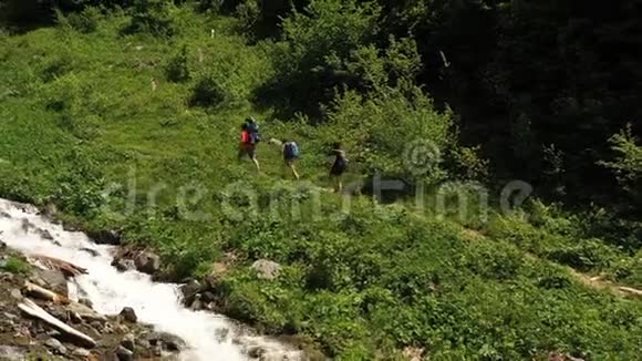 带背包的团体游客沿着快速的山溪漫步视频的预览图