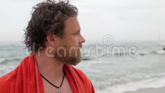 一个留着胡子头湿湿的年轻人游泳后肩膀上挂着一条毛巾贴在大海的背景上4公里视频视频的预览图