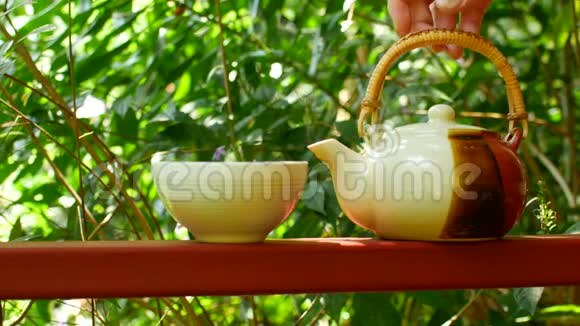 在绿色的背景下茶被倒进杯子里视频的预览图