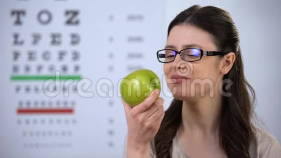 戴眼镜的微笑女士咬新鲜苹果健康营养天然维生素视频的预览图