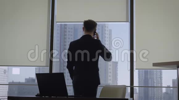 商务人员在办公室窗口打电话然后到工作场所视频的预览图