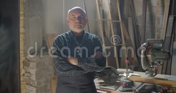 年长的灰发男木匠站在木材制造与交叉的手臂微笑积极的相机视频的预览图