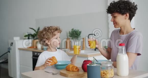 幸福的家庭母子在家喝橙汁吃羊角面包视频的预览图